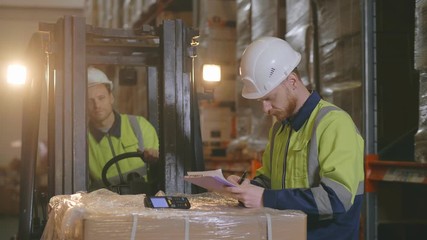 Manual worker on forklift loader and manager with clipboard at industrial warehouse - Powered by Adobe