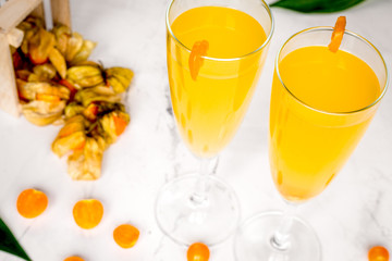 cocktail with physalis in glass on stone background