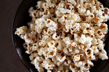 Popcorn in black bowl on black background 