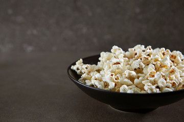 Popcorn in black bowl on black background 