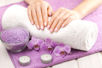 Obraz na płótnie Canvas beautiful pink manicure with decor, orchid, towel and candle on the white wooden table. spa