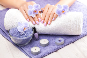 beautiful pink manicure with decor, orchid, towel and candle on the white wooden table. spa