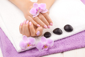 Obraz na płótnie Canvas beautiful pink manicure with decor, orchid, towel on the white wooden table. spa