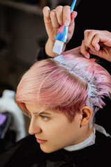 Hairdresser colorist dyes the hair of a woman to a client in different colors.