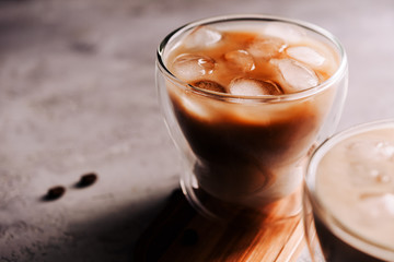 Iced coffee in a glass with ice cubes on concrete background