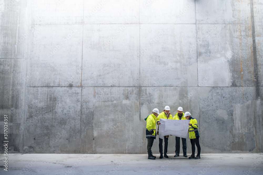 Wall mural a group of engineers standing against concrete wall on construction site. - Wall murals
