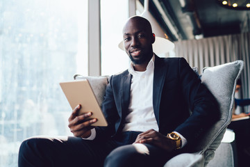 Naklejka na ściany i meble Smiling confident African American executive man using tablet in office