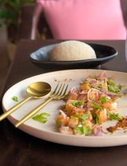Asian cuisine. Diced raw salmon with red onions, lemon and mint, with steamed rice on the side. Close up shot.