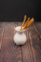 Devices for traditional Chinese tea drinking made of bamboo in a white ceramic vase in the Chinese style on a wooden background. Close up.