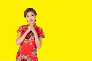 Pretty Asian female with Chinese traditional dress cheongsam or qipao hand showing blank space. Chinese new year concept, female model isolated on yellow background.