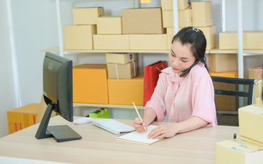 Young business start up online seller owner using computer for checking the customer orders from email or website and preparing packages for product office equipment.
