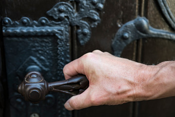 man hand on vintage door knob. Opening or closing wooden door