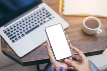 Mockup image blank white screen cell phone.woman hand holding texting using mobile on desk at coffee shop.background empty space for advertise text.people contact marketing business,technology 