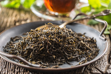 Dried tea leaves in bowl on rustic wooden table