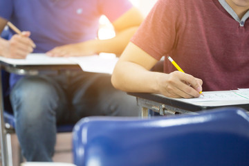 high school,university student study.hands holding pencil writing paper answer sheet.sitting lecture chair taking final exam attending in examination classroom.concept scholarship for education abroad - obrazy, fototapety, plakaty