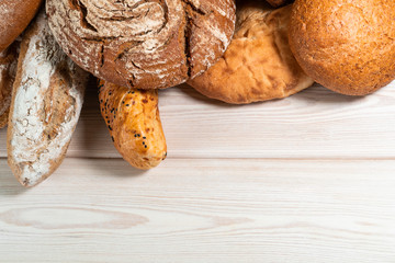 flour in a wooden bowl on dark wooden background with spikelets of wheat, eggs and milk, top view with copy space