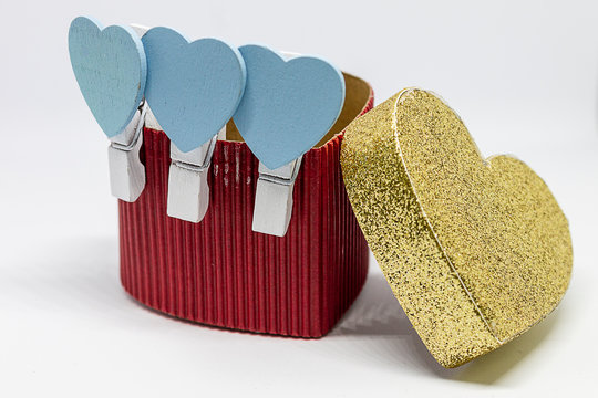 Cajita en forma de coraz&oacute;n con corazones azules en pinzas blancas y un gran coraz&oacute;n dorado.
