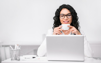 Latin girl drinking tea and using computer