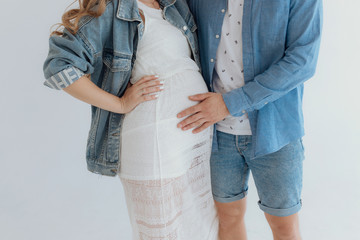 Shot of pretty young pregnant couple in the white room at home.
