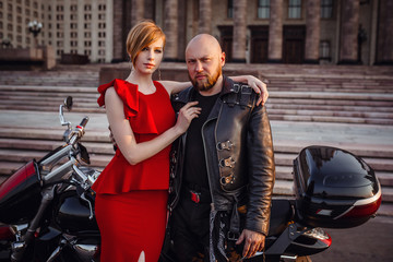 Beautiful unusual couple on a motorcycle against the backdrop of a beautiful stately building in Moscow