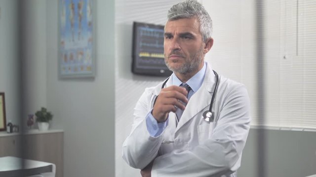 portrait of a thoughtful pensive doctor behind a glass thinking about patient diagnosis 4k