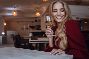 Elegant lady with glass of wine alone in restaurant