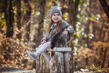 little cute girl and cat in the forest, soft warm light