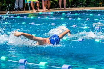 Young boy swimmer doing butterfly stroke at a pool