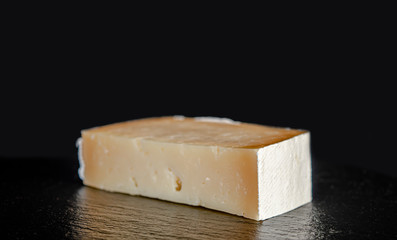 piece of hard cheese on a black background close-up