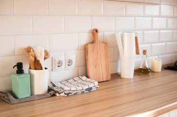 Interior details of light modern kitchen with brushes, towels and chopping board.