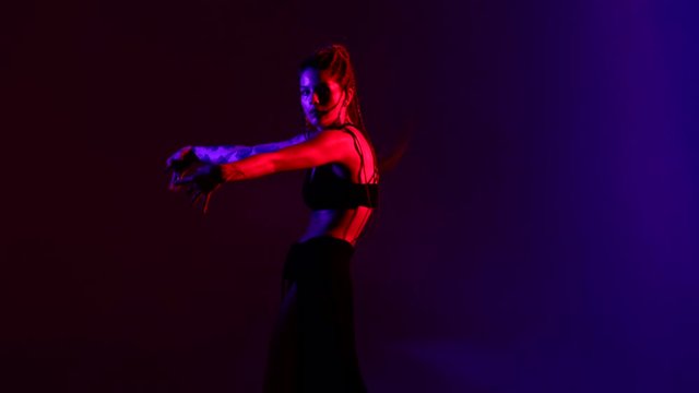 Black dressed and braided hair woman oriental dancing on a blue and red background.
