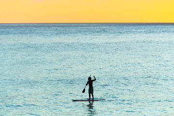 silhouette of man with his stand up paddle with a beautiful sunset background on Ipanema beach.