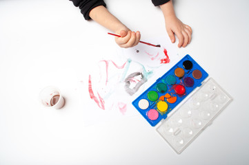 child paints a brush with watercolor honey paints