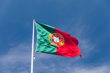 Beautiful large Portuguese flag waving in the wind against blue sky. Portuguese Flag Waving Against...