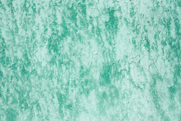 Shabby old fence covered faded green paint with light smudges on stucco. Vintage background for your design. Abstract grunge texture of peeling paint on worn wall.