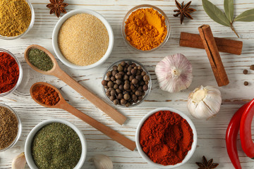 Bowls with spices and ingredients on wooden background, top view