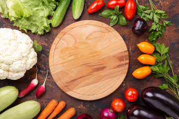Wood plate and fresh farmers garden vegetables on wooden table. Harvest time. Top view