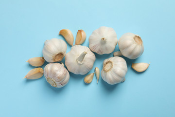 Fresh garlic bulbs, slices on blue background, top view. Space for text