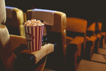Popcorn and 3d glasses on yellow armchair.