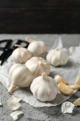 Garlic bulbs, slices, scissors, rosemary on grey background, closeup. Space for text
