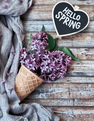 Hello spring chalkboard on wooden backround with a waffle cone with lilac flwoers