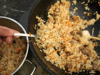 Hand putting cooked pilaf