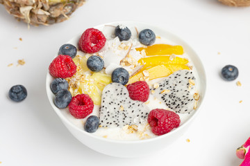 Smoothie bowl with mango, pineapple, dragon fruit, blueberries, raspberries and coconut. Delicious and healthy Breakfast.