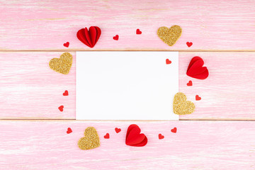 Valentines Day, Birthday Composition. Blank White Greeting Card with Handmade Paper Hearts and Confetti on Pink Wooden Background. Valentine's Day Concept. Top View, Copy Space