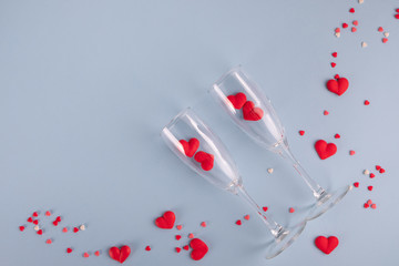 Valentine's Day background. Red candy  hearts and two champagne glasses on pastel blue background. Valentines day concept. Flat lay, top view, copy space