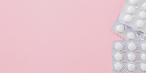 White pills in a blister on a pink background. Medical pharmacy concept
