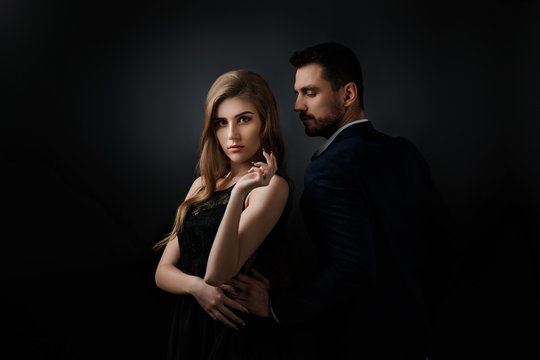 elegant couple on black background. handsome man and beautiful woman in black dress
