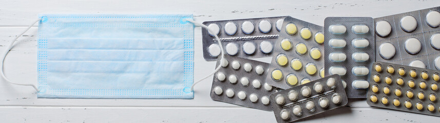 Medical disposable mask, tablets on a white background. The concept of protection during an epidemic of the disease. Copy space. Flat top view