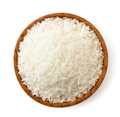 Coconut shavings in a wooden plate close-up, on white background. Top view