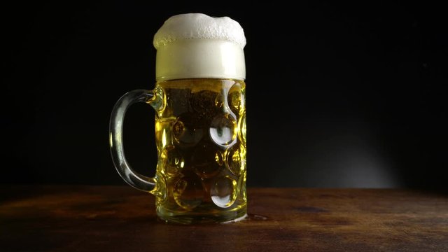  Pouring Beer in a big Oktoberfest Glass on black Background with yellow Light